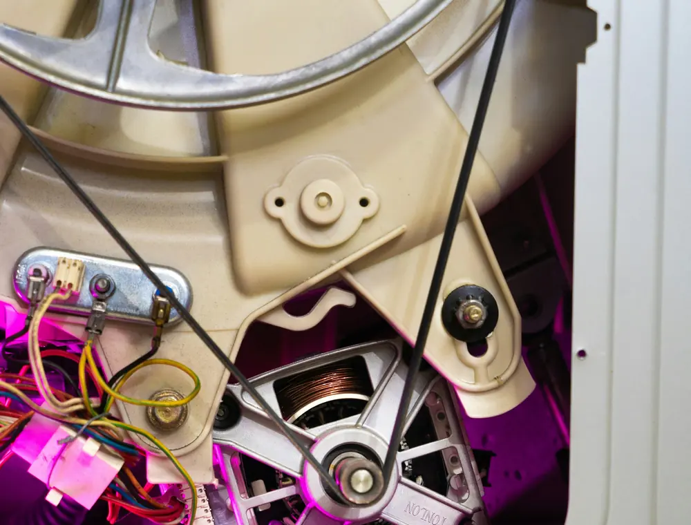 Motor y correa de un electrodoméstico abierto durante la reparación